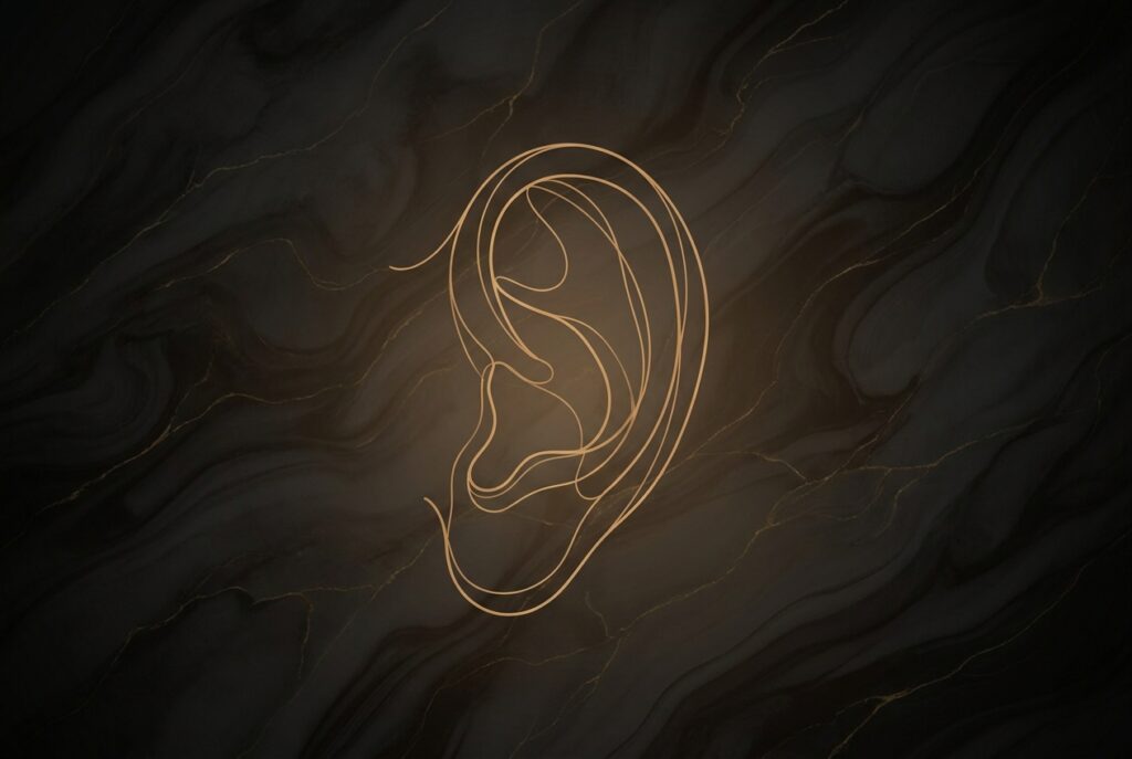 Gold line illustration of a human ear on dark marble